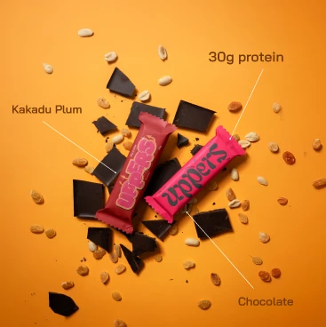 Two bars among broken chocolate and nuts, labelled Kakadu plum and chocolate